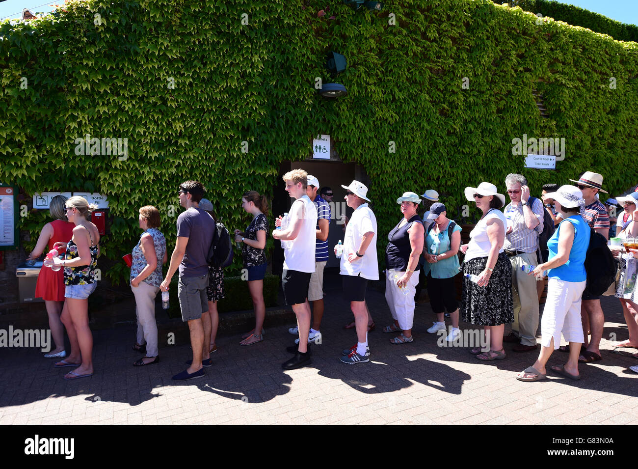 Am zweiten Tag der Wimbledon Championships im All England Lawn Tennis and Croquet Club, Wimbledon, stehen die Zuschauer Schlange, um den Wasserhahn zu benutzen. Stockfoto