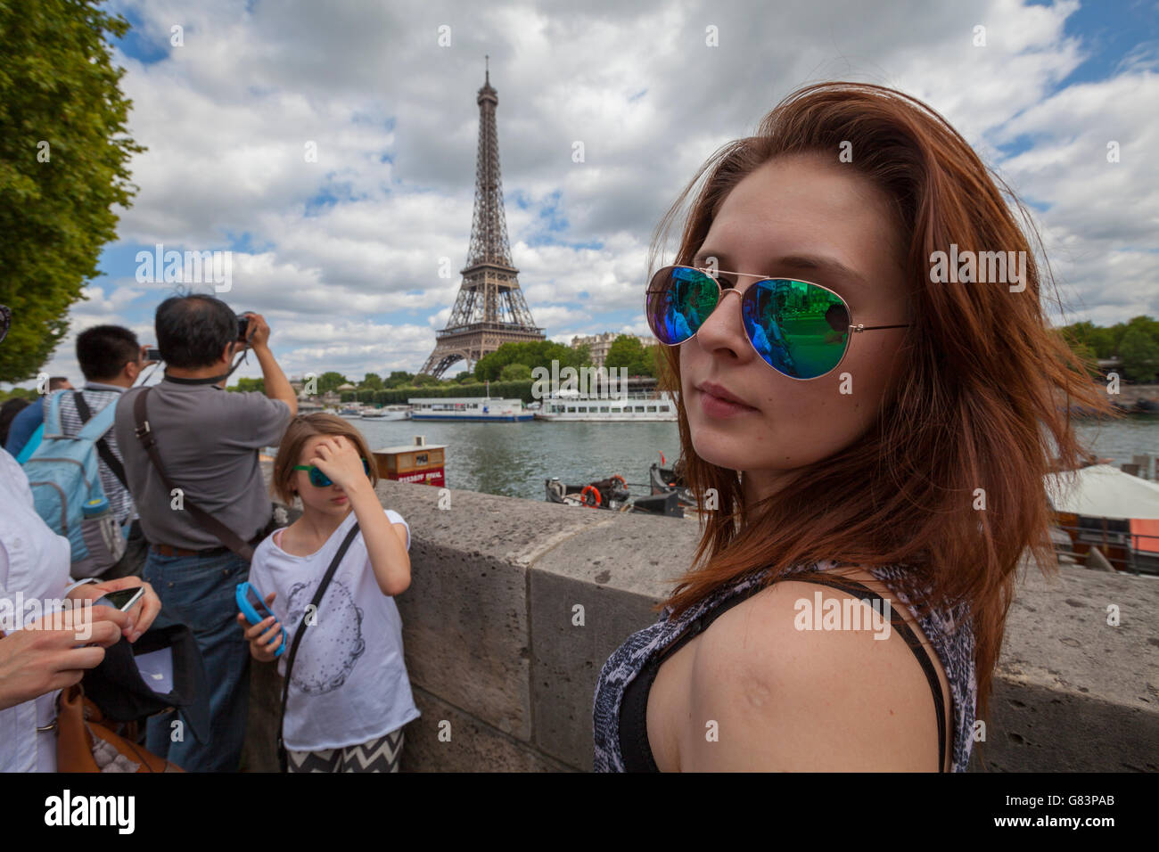 Schöne Mädchen posiert auf dem Seineufer Boulevards mit Eiffelturm (Tour Eiffel) im Hintergrund, Paris, Frankreich Stockfoto