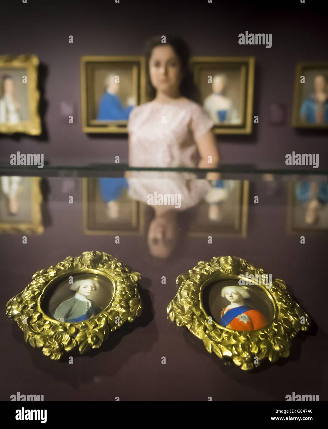 Die Mitarbeiterin der National Galleries of Scotland Adeline Amar spiegelt sich in einem Kabinett wider, das Porträts von Bonnie Prince Charlie (rechts) und seinem Bruder Prince Henry (links) in einer Ausstellung des Künstlers Jean Etienne Liotard aus dem 18. Jahrhundert in der Scottish National Gallery in Edinburgh enthält. Stockfoto