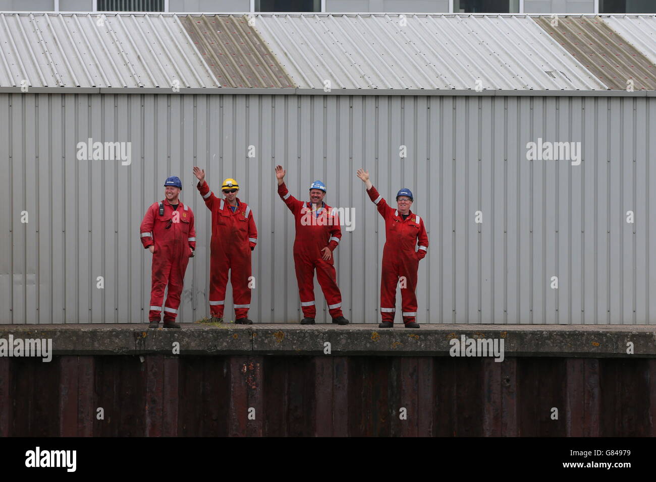 Vier Hafenarbeiter von Harland und Wolff winken von den Tall Ships ab, als sie sich darauf vorbereiten, Belfast nach vier Tagen im Rahmen des maritimen Tall Ships Festival Race zu verlassen. Stockfoto