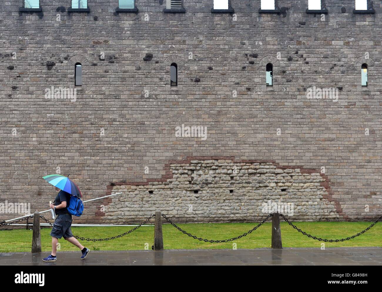 Ein Mann trägt im Regen einen Regenschirm im Cardiff Castle in Cardiff, Wales. Das Vereinigte Königreich ist für milderes Juliwetter eingestellt, aber nicht vor ein paar unruhigen Tagen mit Schauern. Stockfoto