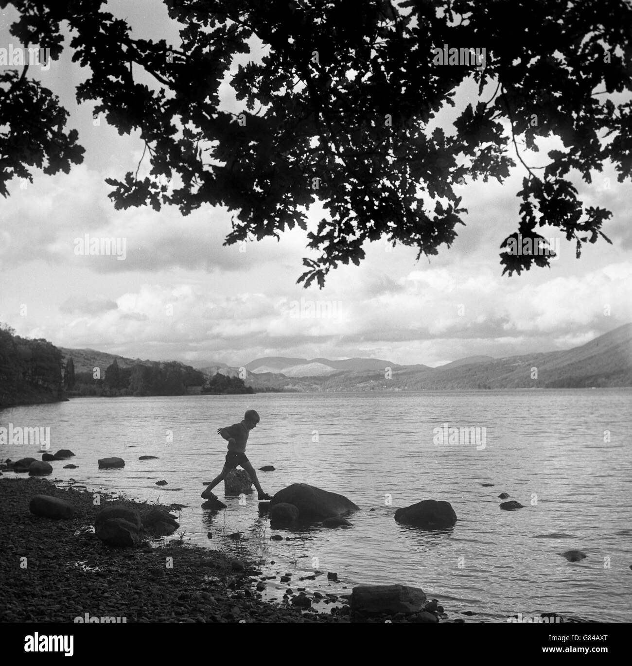 Ein kleiner Junge spielt in den Untiefen des Lake Coniston im Lake District. Stockfoto
