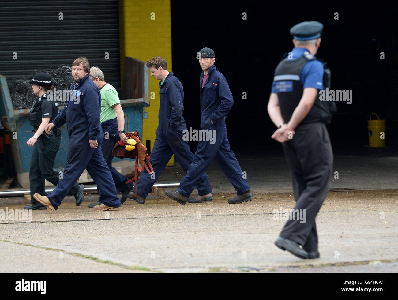 Mitarbeiter folgen der Polizei vor dem Baggerschaufelhersteller Harford Attachments in Spar Road, Hellesdon, Norwich, wo zwei Männer nach einer Explosion auf dem Industriegebiet ums Leben kamen. Stockfoto