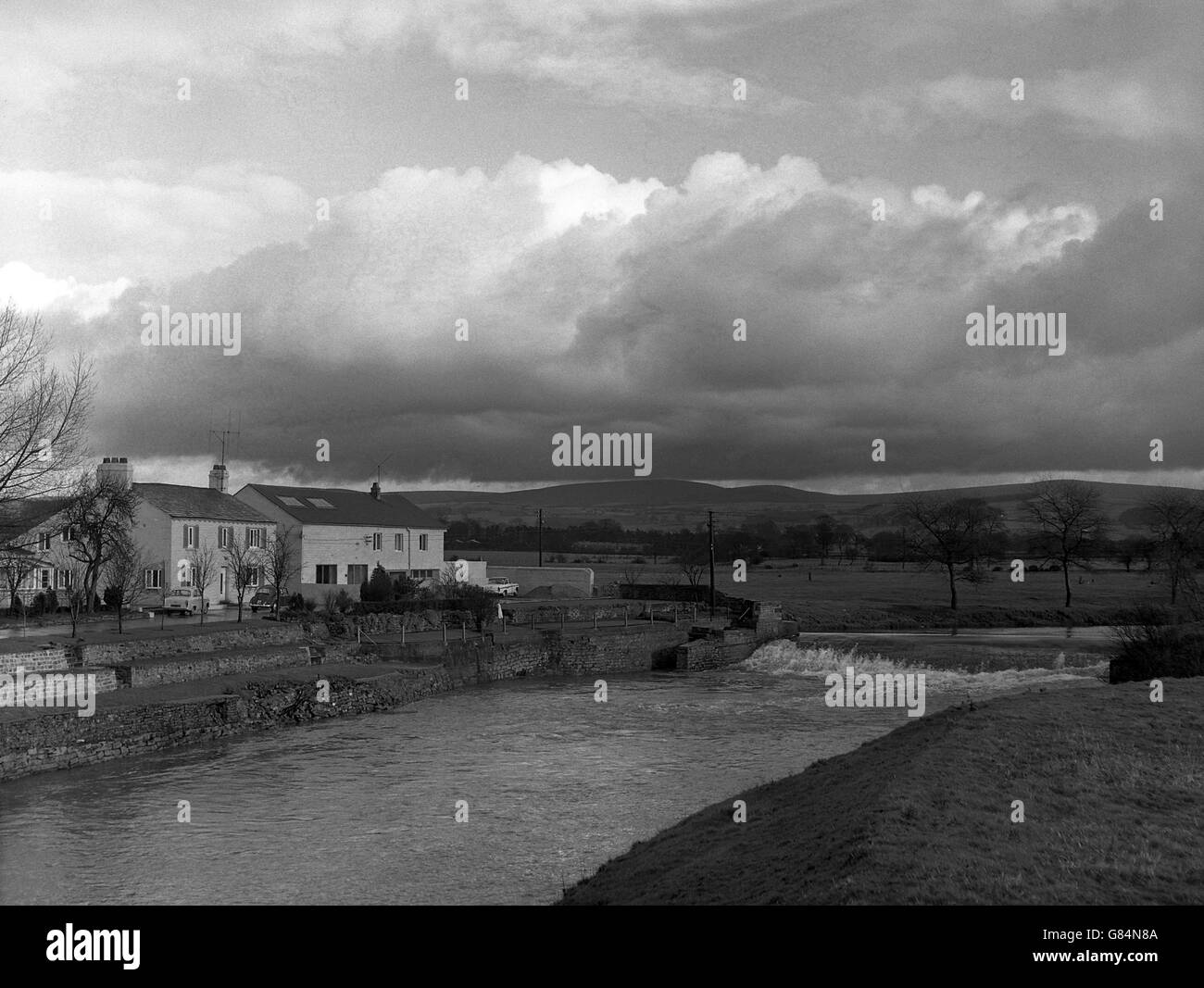 Ein Abschnitt des Flusses Wyre neben einem Mühlenhaus in der Nähe von Garstang in Lancashire, von der A6 Preston-Lancaster Road. In der Ferne befinden sich die Bleasedale Fells. Stockfoto