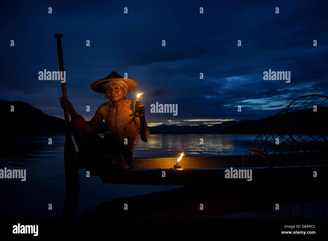 Mann sitzt im Fischerboot bei Sonnenuntergang, Mekong-Fluss, Thailand Stockfoto