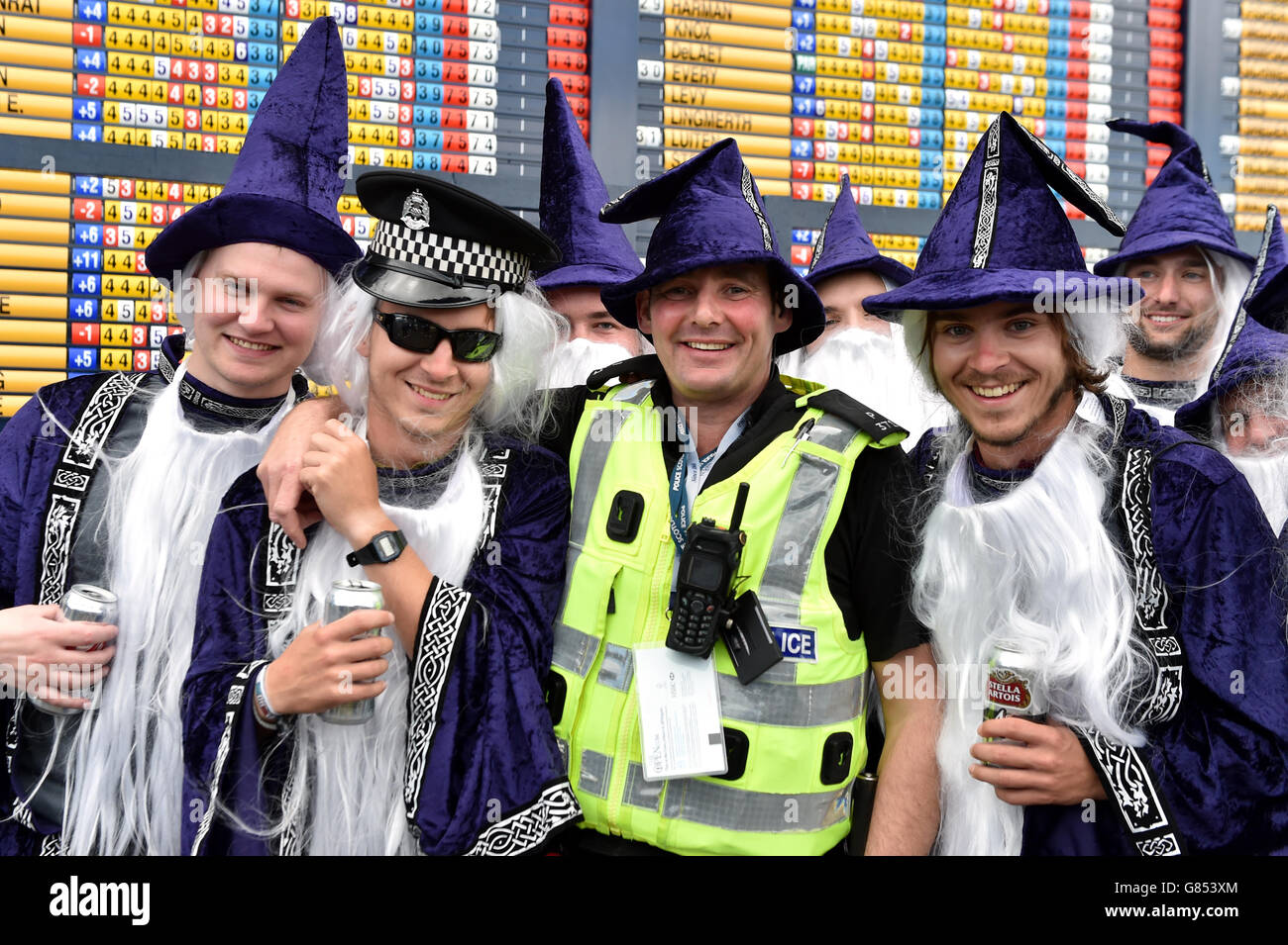 Eine Gruppe von Golffans in schicken Kleidern posieren für ein Foto mit einem Polizisten während des dritten Tages der Open Championship 2015 in St Andrews, Fife. Stockfoto