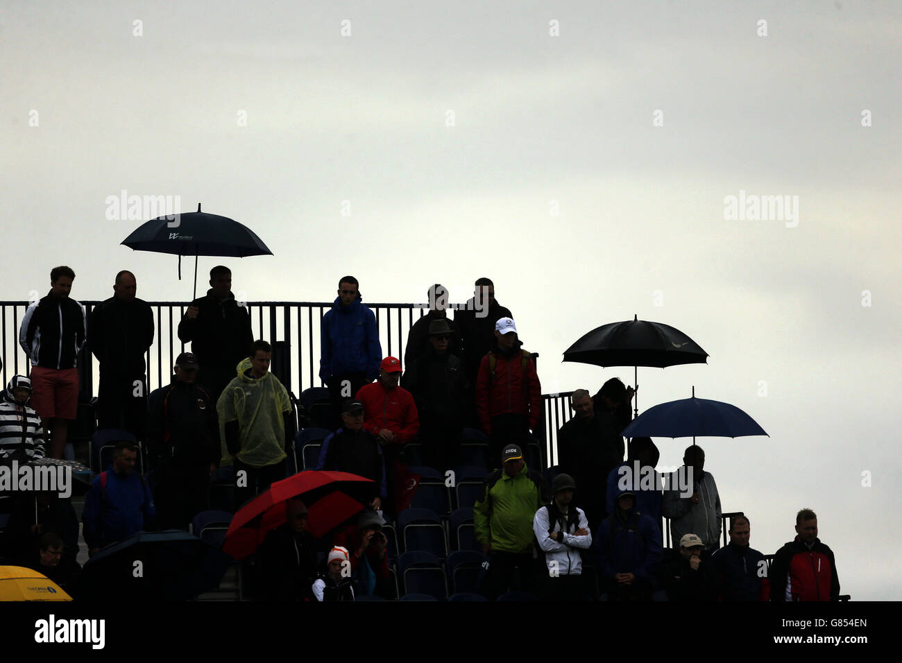 Ein Schattenbild, während die Zuschauer die ersten Gruppen des Tages am vierten Tag der Open Championship 2015 in St Andrews, Fife, unter Regenschirmen beobachten. Stockfoto