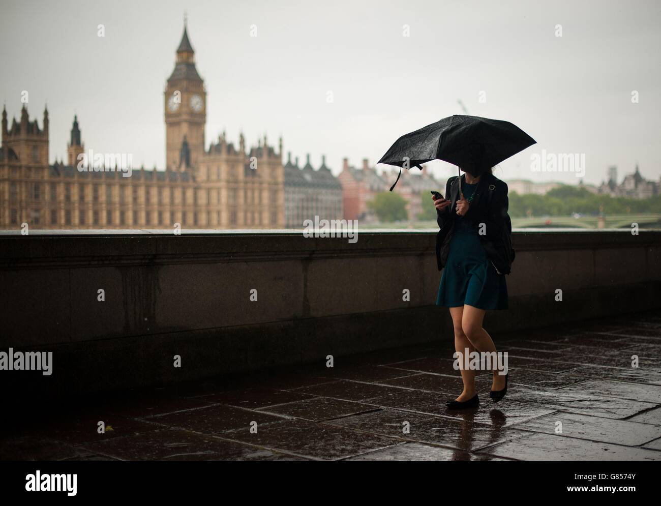 Eine Frau unterzieht sich unter einem Regenschirm, als sie in der Nähe der Houses of Parliament in Westminster, London, geht, da Teile von Großbritannien von sehr starkem Regen und Winden von bis zu 50 mph in einem "intensiven" Tag mit ungewöhnlich schlechtem Wetter geschlagen werden. Stockfoto