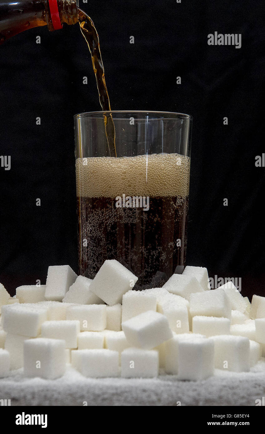 Ein kohlensäurehaltiges Getränk, das von Zuckerwürfeln umgeben ist, könnte laut Forschung fast 8,000 Fälle von Typ-2-Diabetes pro Jahr verursachen. Stockfoto