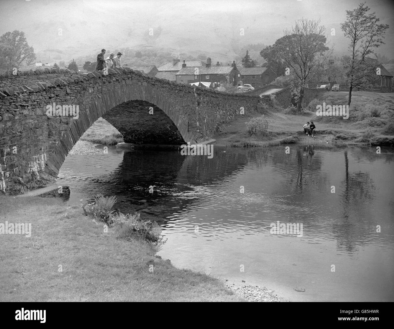 Grange in Borrowdale. Der Fluss Derwent fließt unter der alten Steinbrücke, ein beliebter Aussichtspunkt, um Forellen und gelegentlich Lachs im kalten Wasser zu beobachten, das aus dem Great Gable Berggebiet fließt. Stockfoto