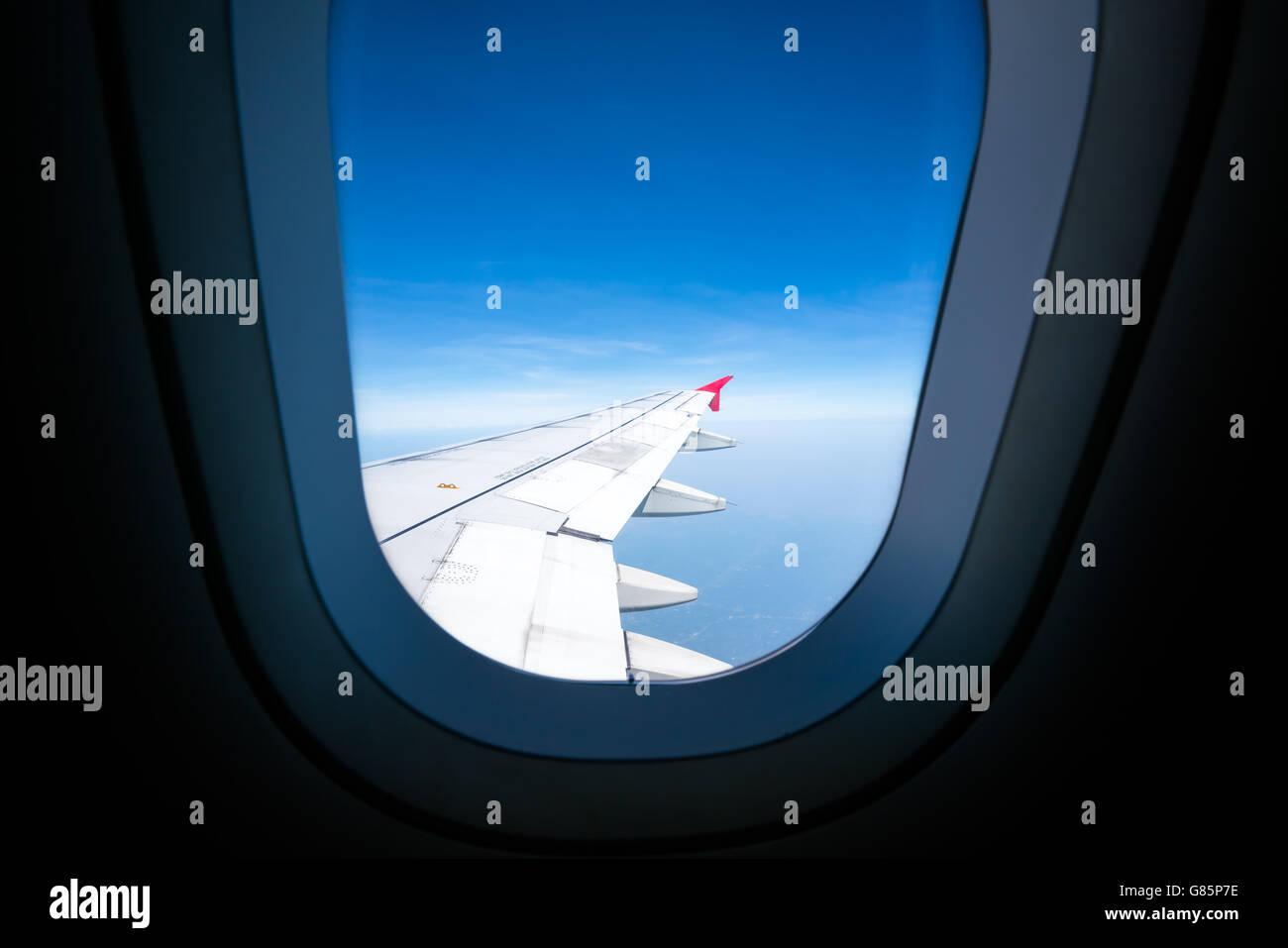 Flugzeugflügel auf blauen Himmel Blick durchs Flugzeugfenster mit Textfreiraum Stockfoto
