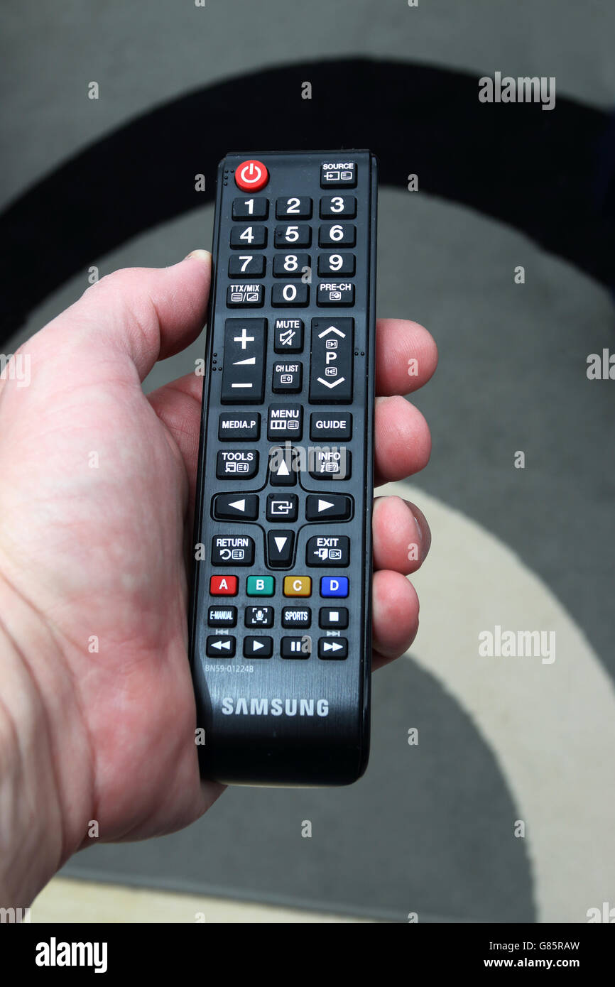 Nahaufnahme eines erwachsenen männlichen linke Hand hält Samsung schwarz Fernbedienung für TV Stockfoto
