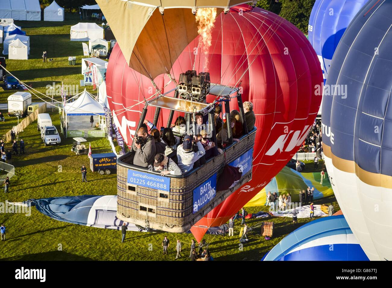 Menschen machen Fotos und Videos, die in einen Korb gepackt sind, während Heißluftballons während der ersten Massenbesteigung beim 37. Bristol International Balloon Fiesta, Bristol, über Ashton Court Estate abheben. Hier fliegen Ballonpiloten und Crews aus der ganzen Welt über die Stadt, um über den Himmel von Somerset und South West in Großbritannien zu fliegen. Stockfoto