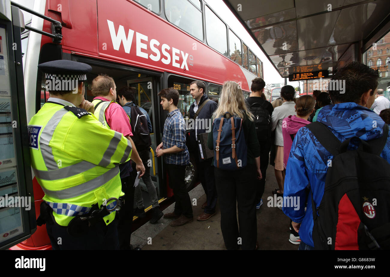 Ein Polizeibeamter beobachtet Pendler, die vor dem Bahnhof King's Cross in London in einen Bus steigen, während Pendler und Touristen aufgrund eines Streiks, der die U-Bahn geschlossen hat, einem Reisesoos ausgesetzt sind. Stockfoto