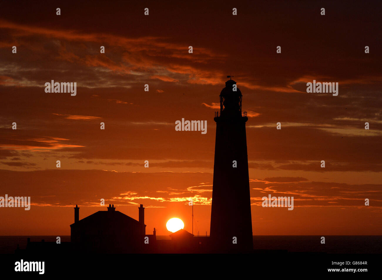 Ein schöner Start in den Tag, wenn die Sonne hinter dem St Mary's Lighthouse in der Nähe von Whitley Bay auf Tyneside aufgeht. Stockfoto