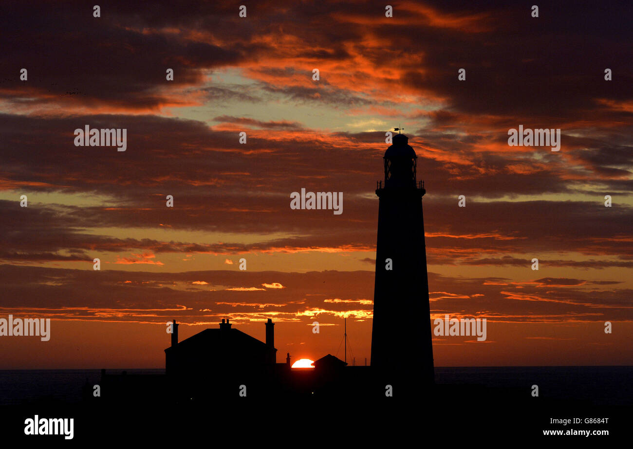 Ein schöner Start in den Tag, wenn die Sonne hinter dem St Mary's Lighthouse in der Nähe von Whitley Bay auf Tyneside aufgeht. Stockfoto