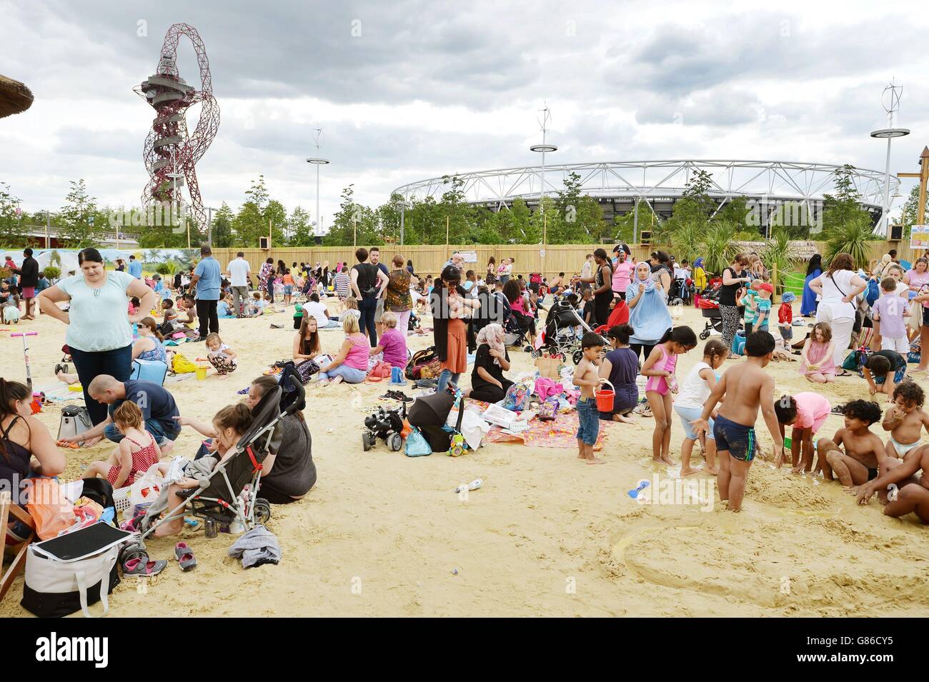 Ein großes Publikum genießt das warme Wetter am künstlichen Strand im Queen Elizabeth Olympic Park in Stratford, Ost-London, mit dem ArcelorMittal Orbit und dem Olympiastadion im Hintergrund. Stockfoto