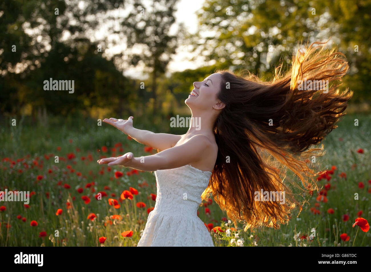 Frau mit ausgestreckten Armen und Haare im Wind wehen Stockfoto