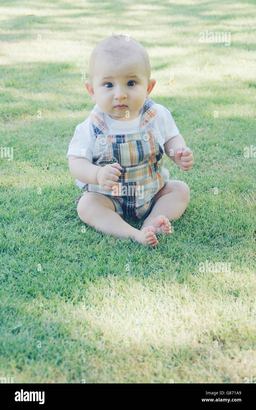 Baby Junge saß auf dem Rasen Stockfoto