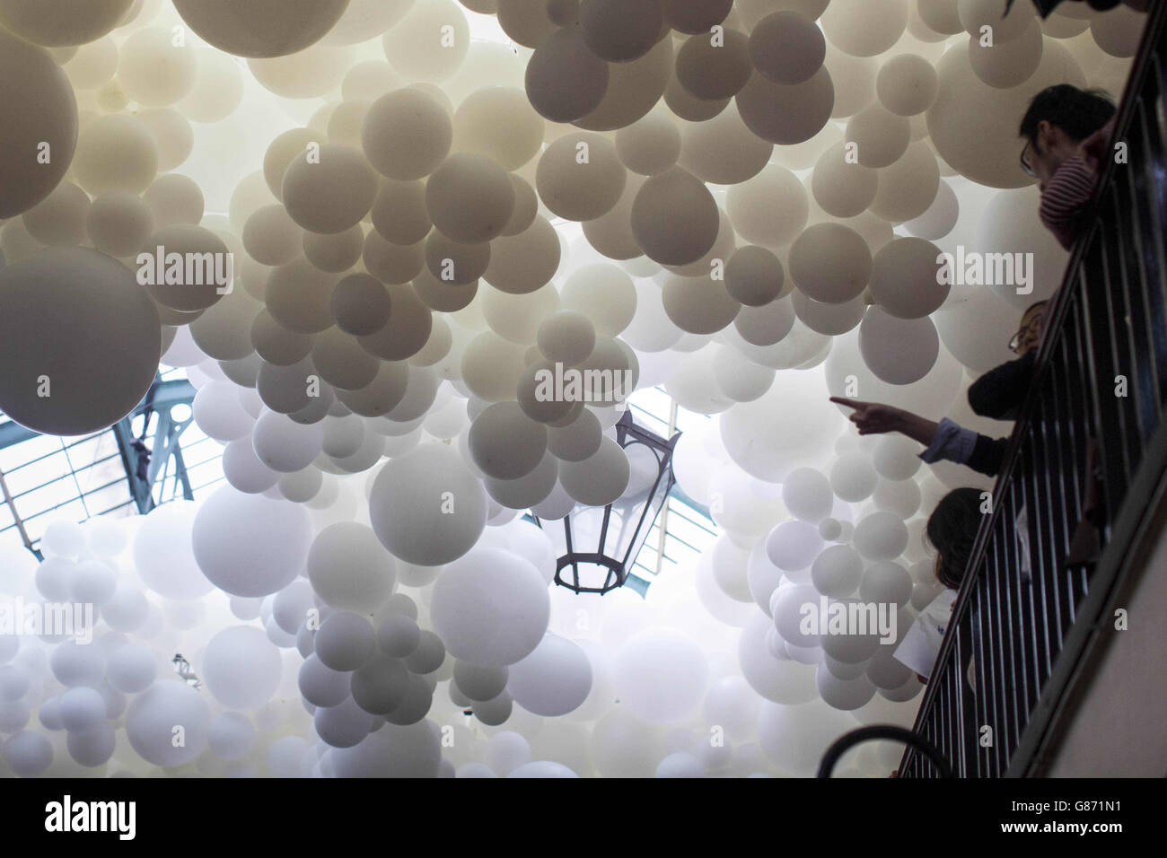 Die Besucher blicken auf Tausende von weißen Ballons, die im Rahmen einer Installation des französischen Künstlers Charles Pestillon in der South Hall of Covent Garden Market im Zentrum Londons platziert wurden. Stockfoto