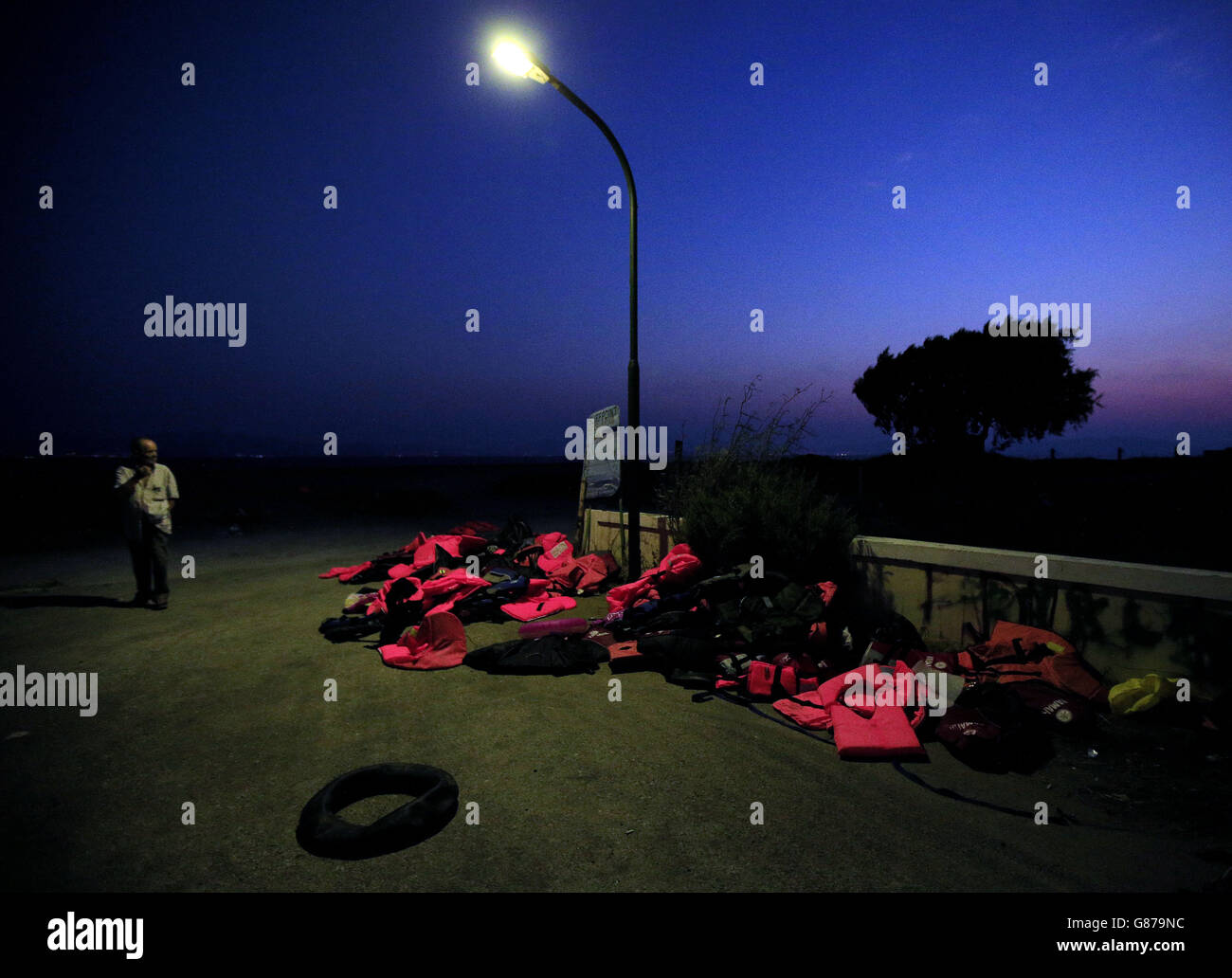 Ein Besucher am frühen Morgen am Strand von Psalidi blickt auf die Rettungsanker, die kürzlich in Kos, Griechenland, angereist sind. Stockfoto