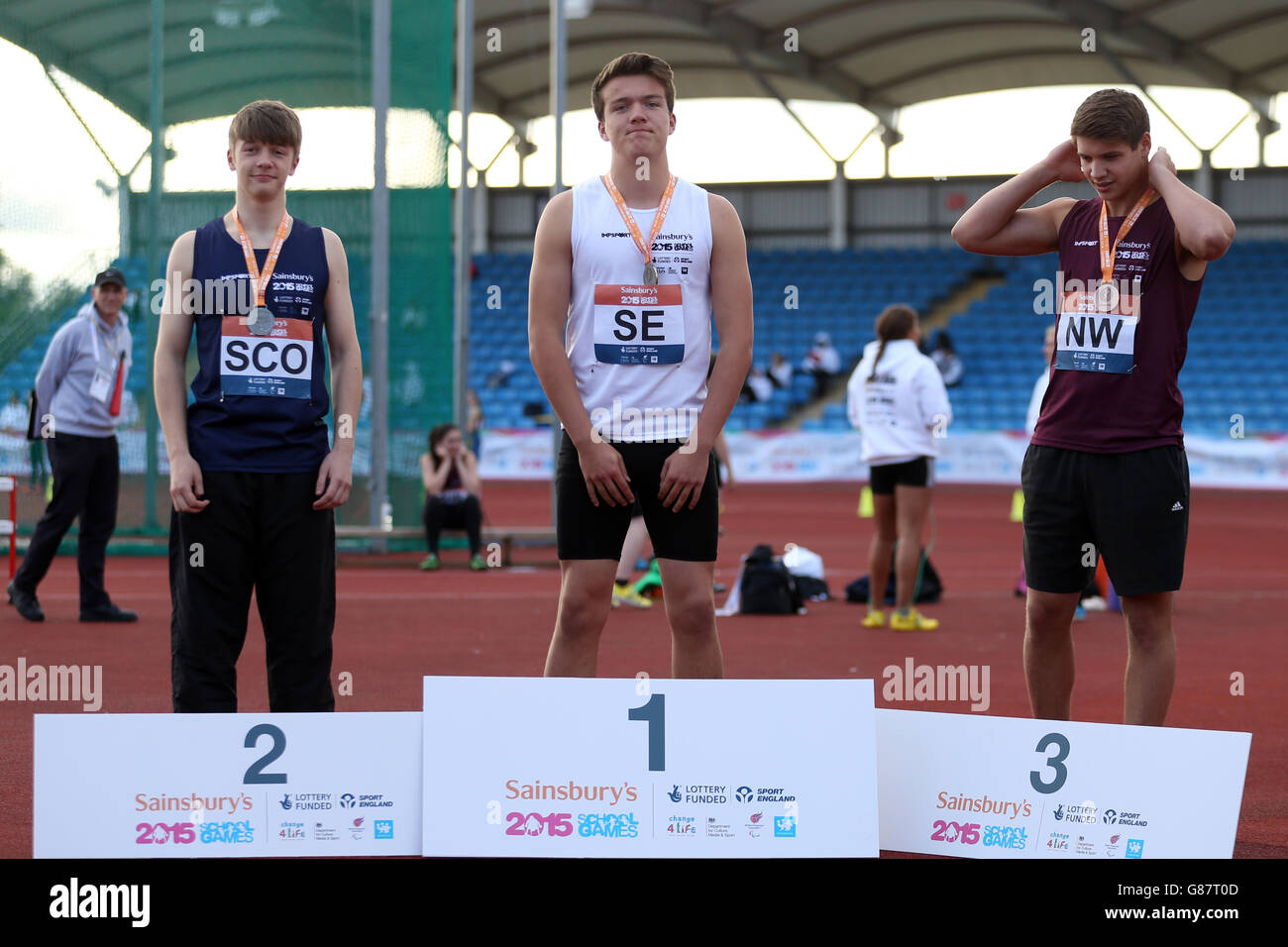 (l-r) der schottische Andrew Peck, die Alfie Scopes von England South East und das Charlie Headdock von England North West erhalten ihre Jungen, die während der Medaillenzeremonie bei den Sainsbury's School Games 2015 in der Manchester Regional Arena über Medaillen diskutieren. Stockfoto