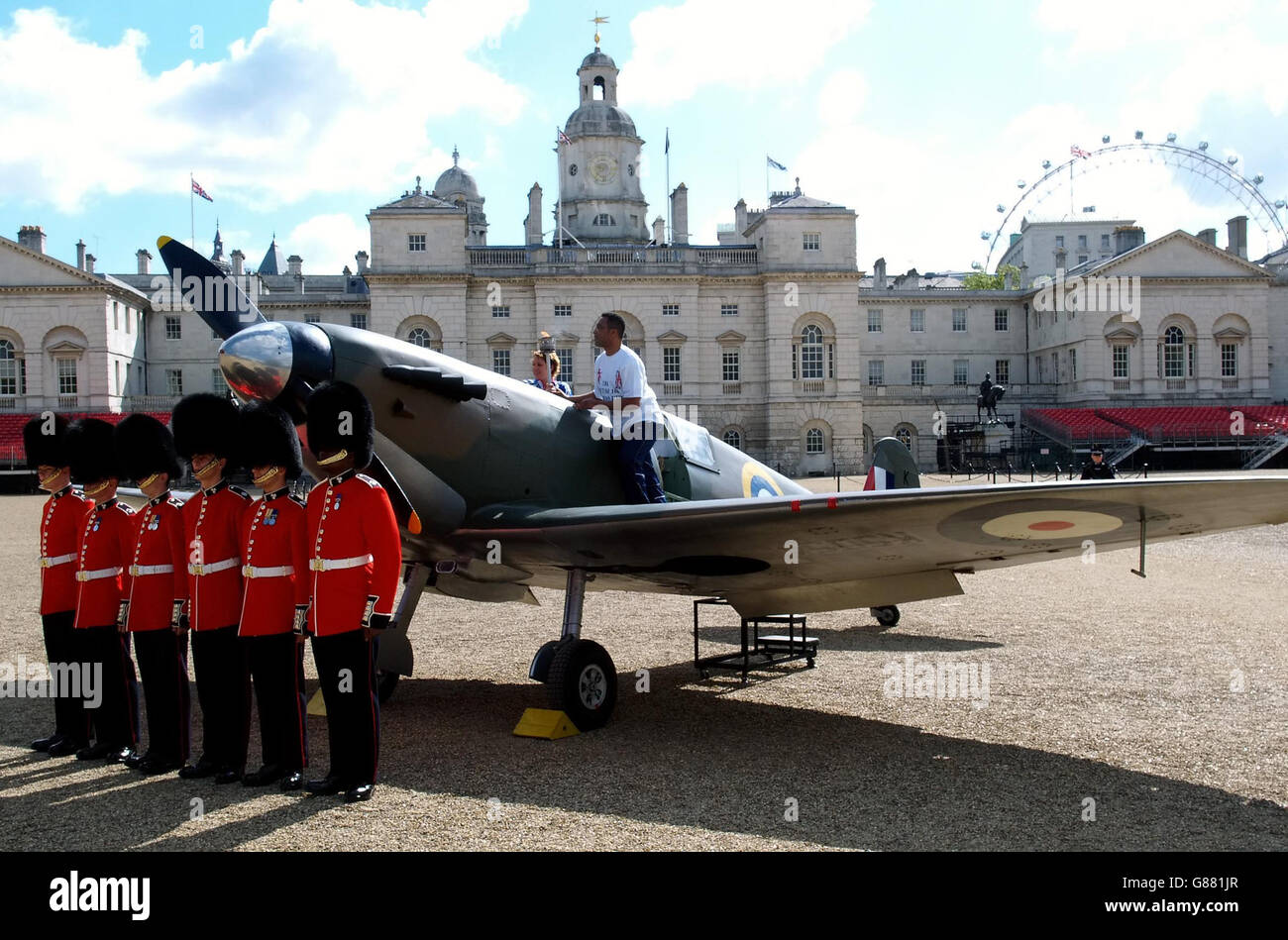 Der ehemalige Boxer Michael Watson (im Flugzeug) und die Soldaten des 1. Bataillons der irischen Garde halten in der Horse Guards Parade eine kurze Zeremonie vor einem Nachbau des Spitfire-Kämpfers 1939 ab. Das Flugzeug wird bei Feiern rund um den 60. Jahrestag des VE-Tages und bei Veranstaltungen rund um die Olympischen Spiele 2012 in London eingesetzt. Stockfoto