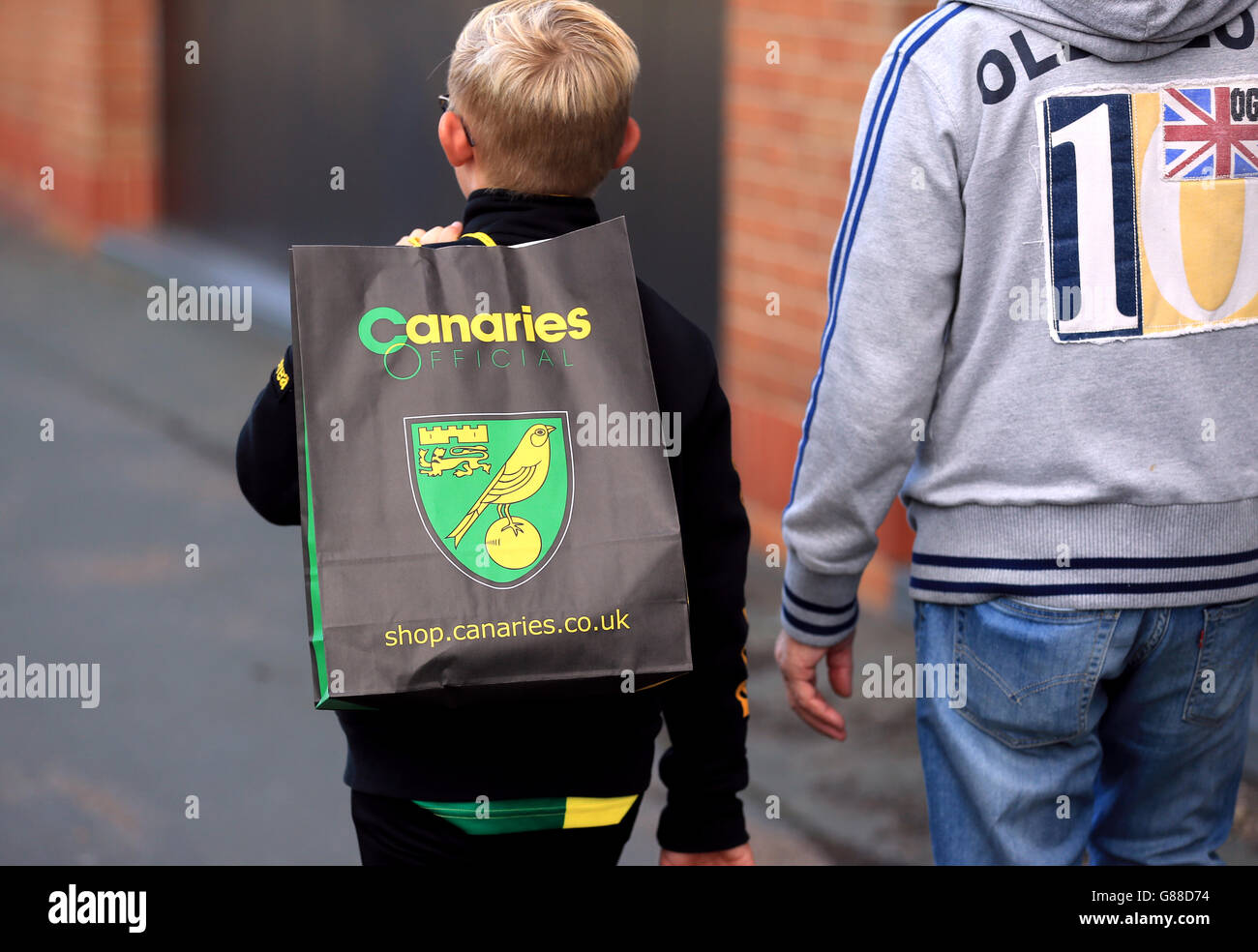 Ein junger Fan von Norwich City führt einen offiziellen Kanarischen Einkaufsbummel Tasche Stockfoto