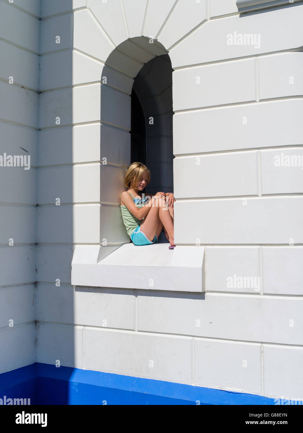 Ein junges Mädchen sitzt in einem Fenster am Leuchtturm von Byron Bay, Byron Bay, NSW, Australien Stockfoto