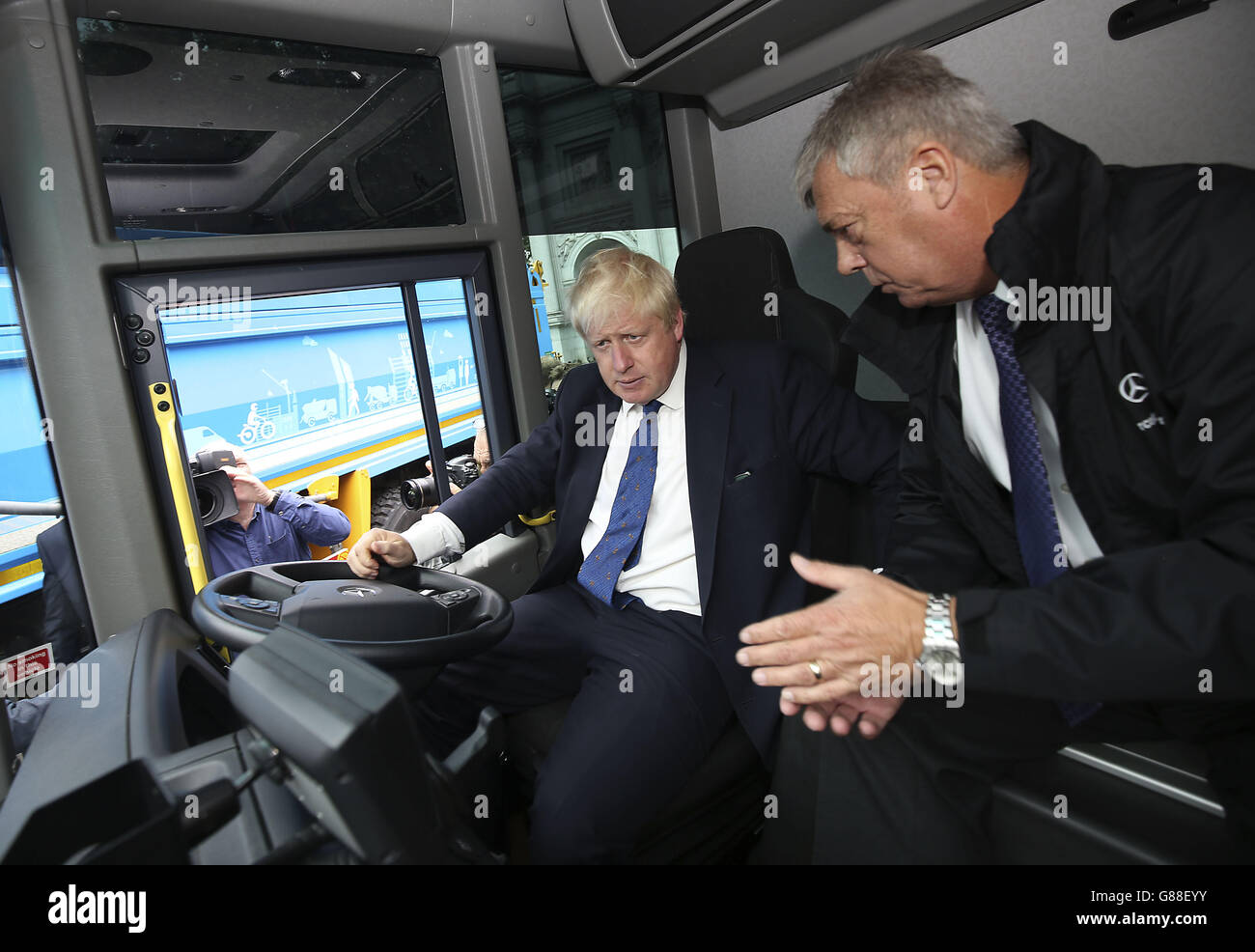 Der Bürgermeister von London, Boris Johnson, wird beim Start des ersten LKW-Programms in London in Marble Arch vom Mercedes-Benz Leiter der Spezialfahrzeuge Basil Vinnicombe ein Fahrerhaus eines Lastwagens gezeigt. Stockfoto