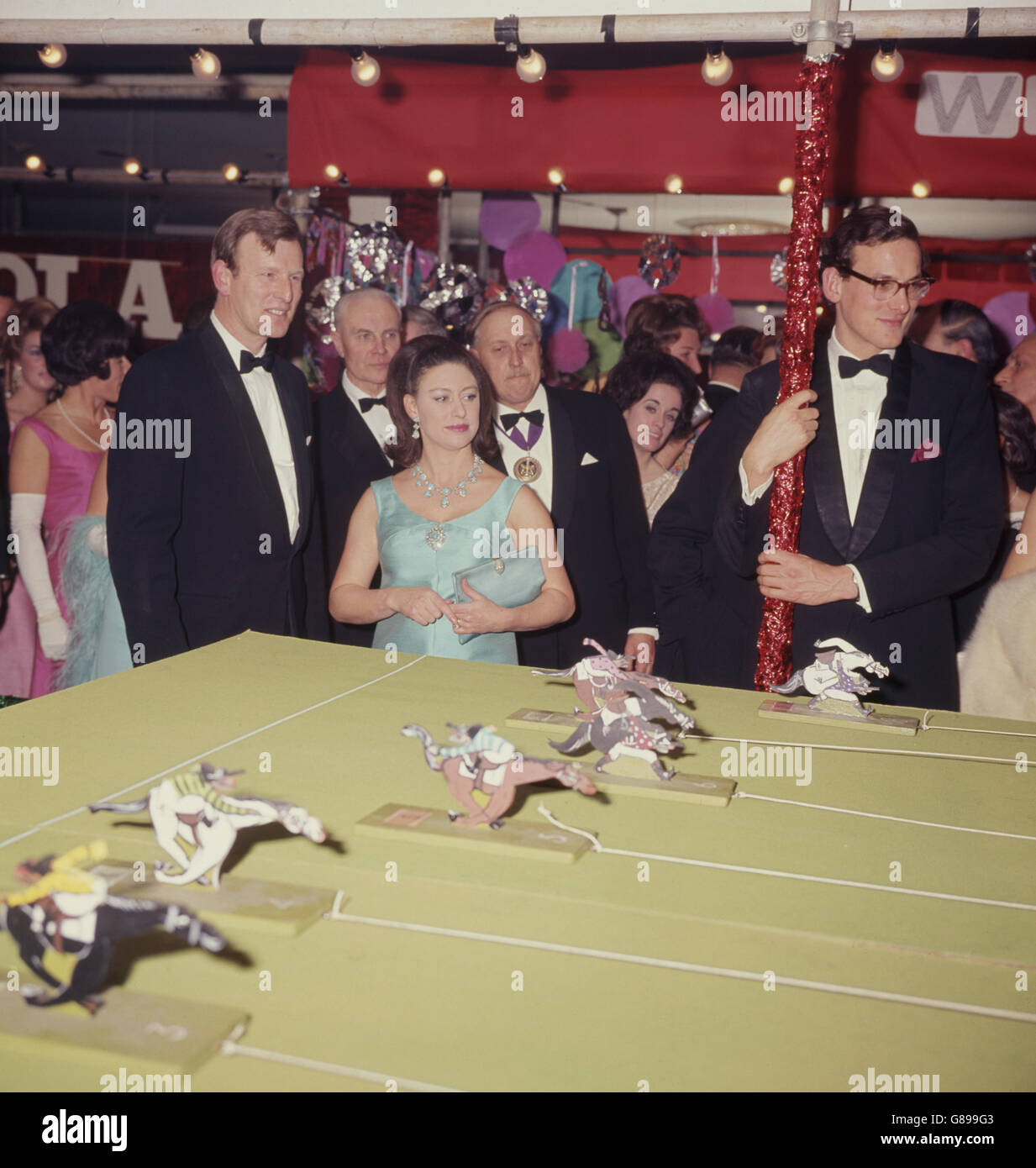 Prinzessin Margaret sieht sich ein Pferderennen-Spiel an, eine der Nebenveranstaltungen auf dem Ball, der für die Architects Benevolent Society im Grosvenor House, London, gehalten wird. Mit ihr ist Herr Peter Watson, Vorsitzender des Sideshow-Komitees. Stockfoto