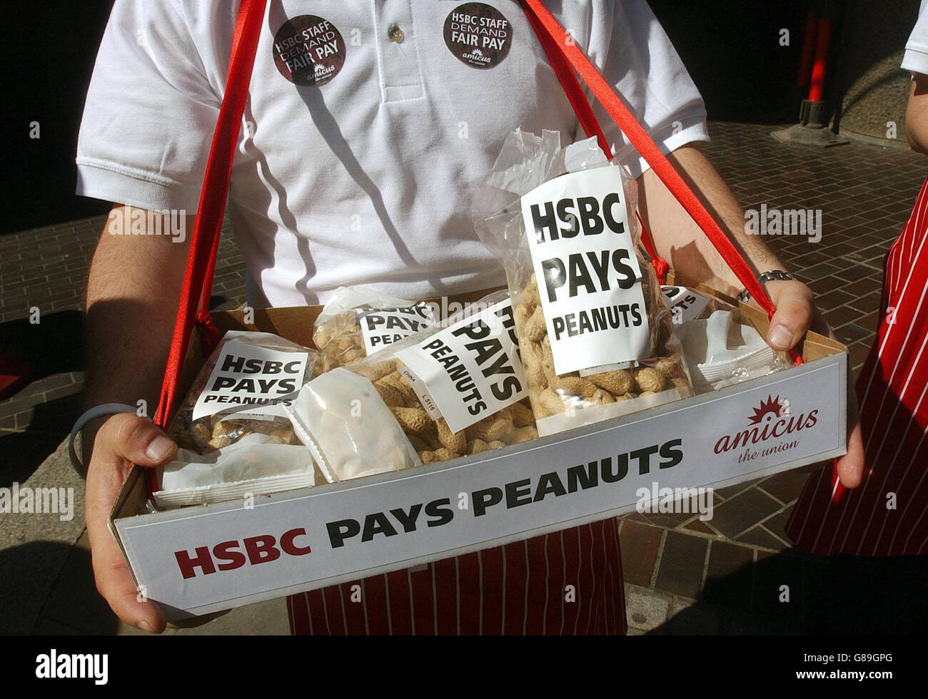 AMICUS-Mitglieder geben den Teilnehmern der HSBC-Hauptversammlung in London Erdnüsse aus, was darauf hindeutet, dass die Bank niedrige Löhne an die Mitarbeiter zahlt. Stockfoto