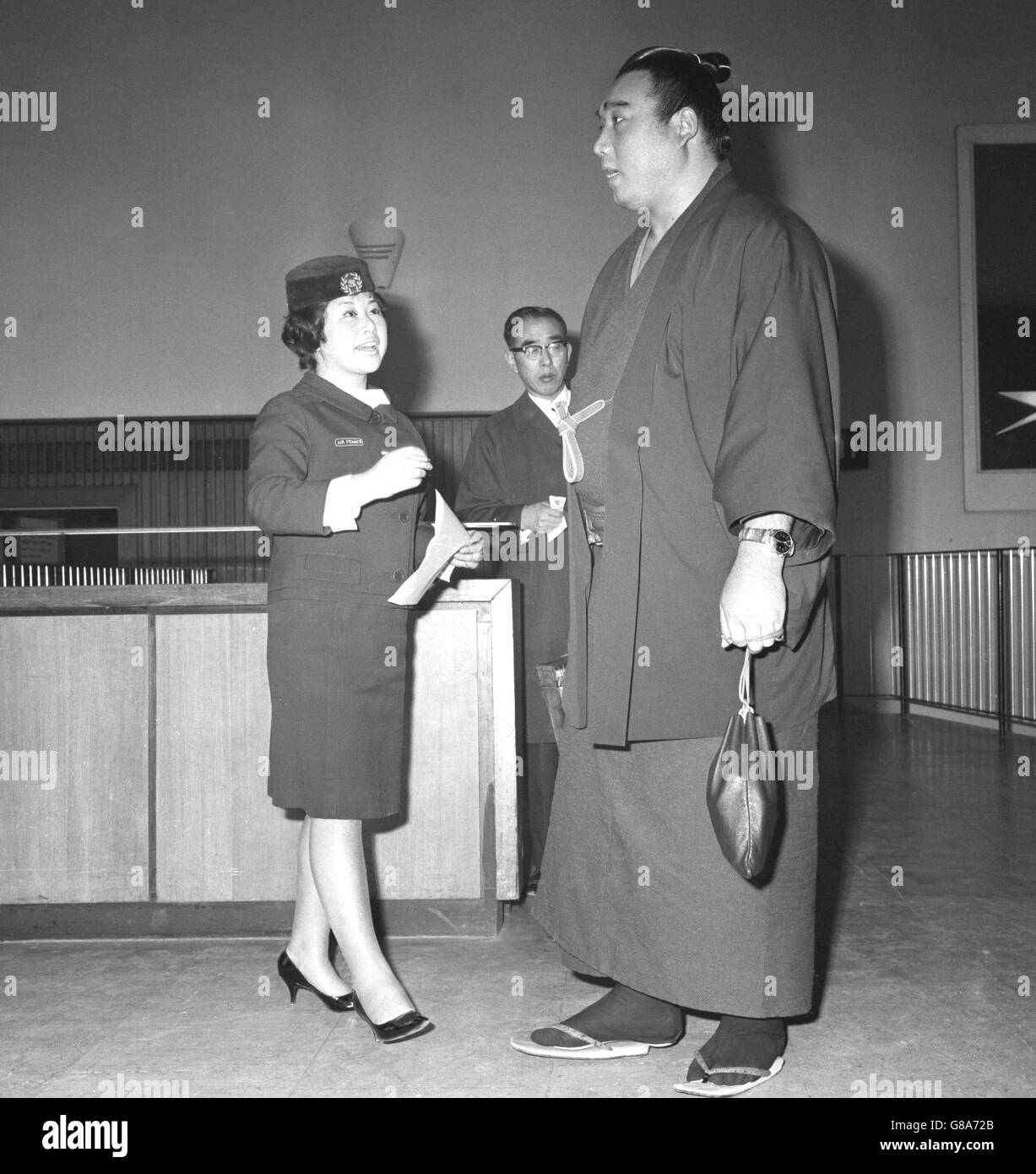 Kashiwado, Weltmeister Sumo Wrestler aus Japan, überragt die Gastgeberin Chiyo Kawasaki am Flughafen London. Kashiwado ist in Großbritannien auf der Welttournee, die Teil seines Preises für den Gewinn der Meisterschaft war. Stockfoto