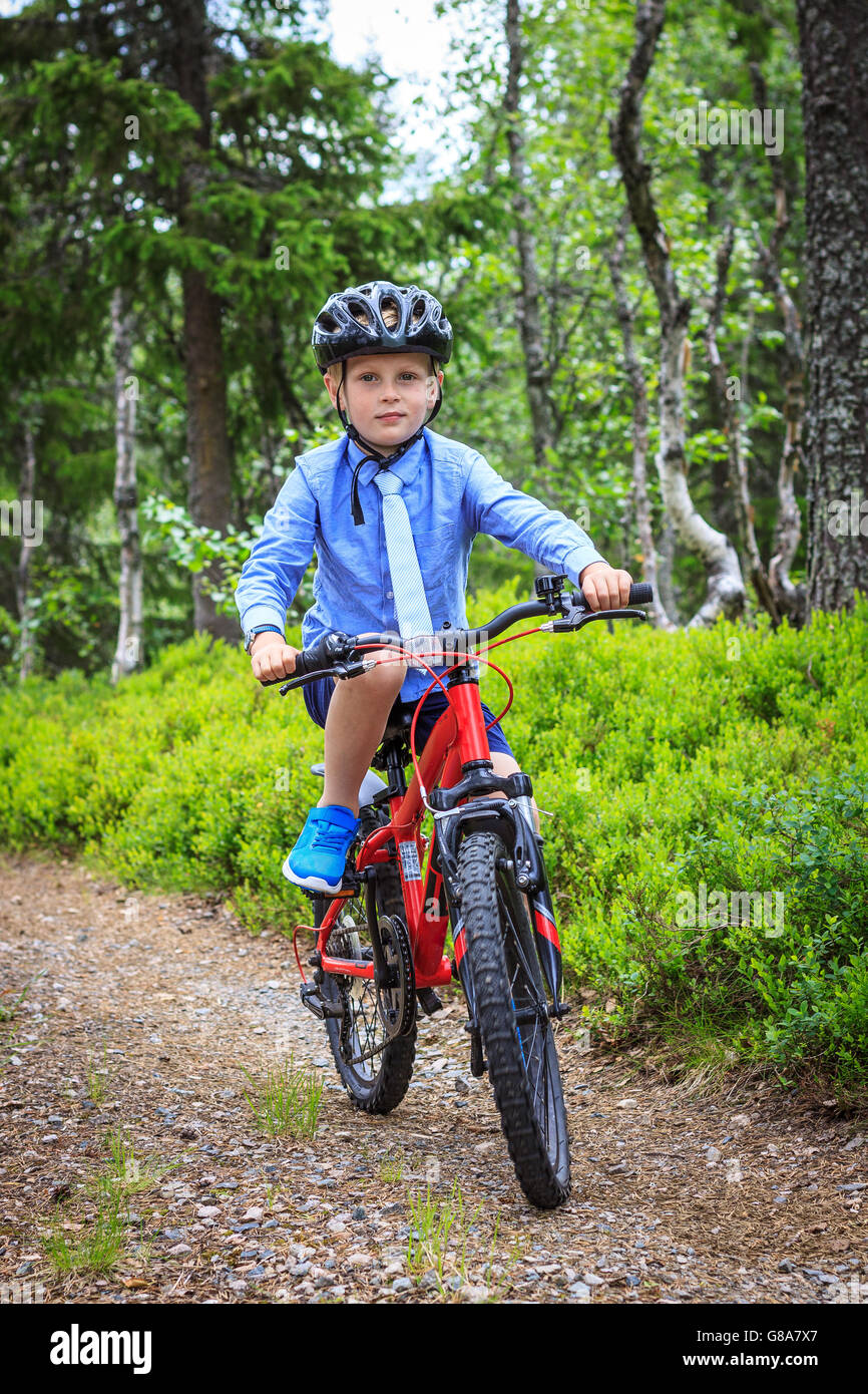Formell gekleidet junge mit Krawatte, roter Berg Radfahren auf einem Schotterweg in den Wald. Sommer ohne Sonne. Das Tragen eines Helmes. Stockfoto