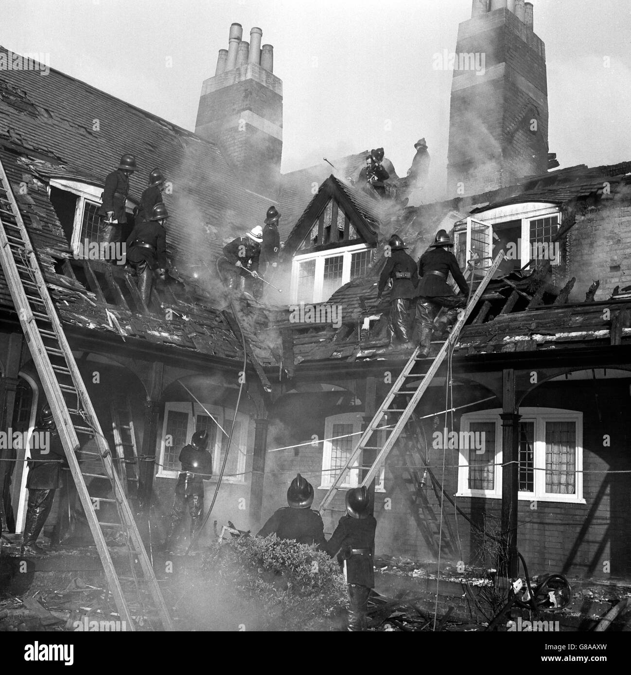 Feuerwehrmänner arbeiten auf dem Dach während eines Feuers, bei dem eine Frau in den Skinners Alms Houses, Palmers Green, starb. Stockfoto