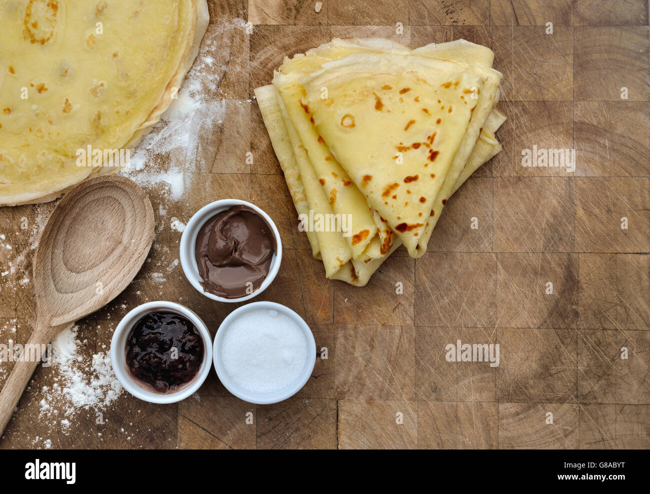 hausgemachte französische Pfannkuchen mit Beilagen in Schüsseln auf Holzbrett Stockfoto