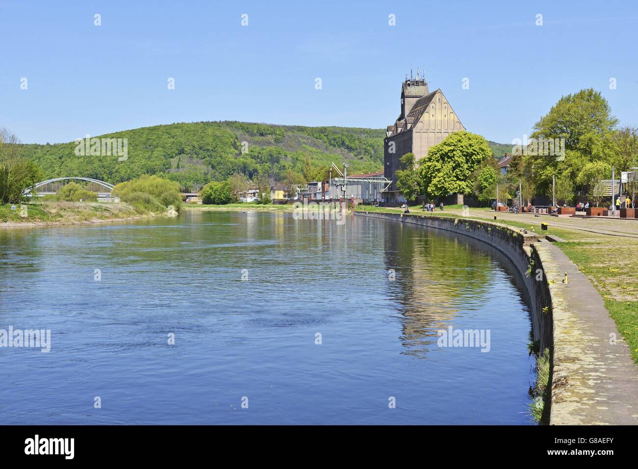 Steinige Kai am geschwungene Ufer der Weser mit einem großen Getreidesilo in der Stadt Holzminden, 5. Mai 2016 | weltweite Nutzung Stockfoto