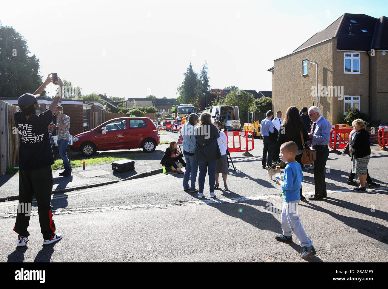 Die Bewohner versuchen, einen genaueren Blick auf eine Sinkhole zu werfen, die sich in einer Wohnstraße in St. Albans eröffnet hat. Stockfoto