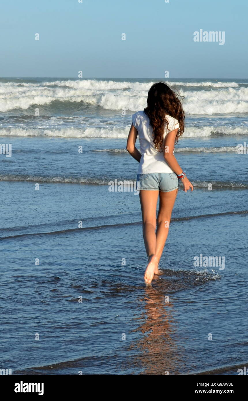 Rückansicht des Mädchen Strand entlang spazieren Stockfoto