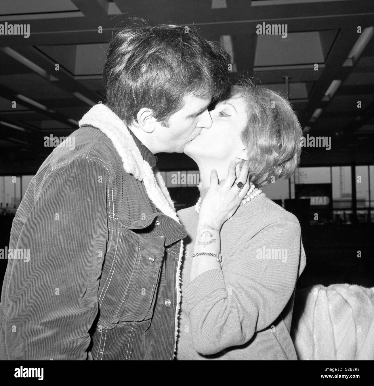 Der Schauspieler David Buck küsst die Schauspielerin Maxine Audley, bevor er den Flughafen London nach Amerika verlässt, um in The Taming of the Shrew für CBC TV zu erscheinen. An ihrem Handgelenk hat Maxine ein "Tattoo" gezeichnet von David mit einem Biro. Sie hat versprochen, es nicht zu entfernen, bis er zurückkehrt. Stockfoto