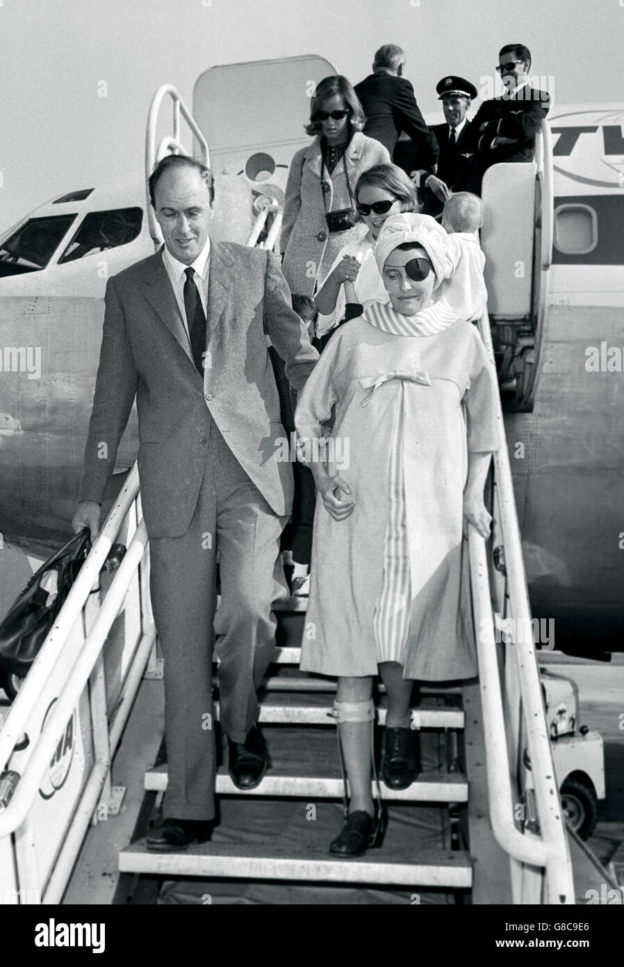 Zurück in Großbritannien ist die Schauspielerin Patricia Neal zu sehen, die von ihrem Mann, dem britischen Schriftsteller Roald Dahl, begleitet wird, als sie nach ihrer Rückkehr aus Hollywood die Stufen vom Flugzeug aus am Flughafen London hinuntergeht. Das Paar wurde von ihren drei Kindern, den Töchtern Tessa und Ophelia und dem Sohn Theo, begleitet. Stockfoto