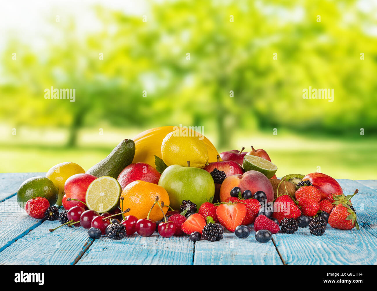 Frisches Obst Haufen gelegt auf Holzplanken, blur Garten auf Hintergrund. Konzept der gesunden Ernährung, Antioxidantien und Sommerzeit. Stockfoto