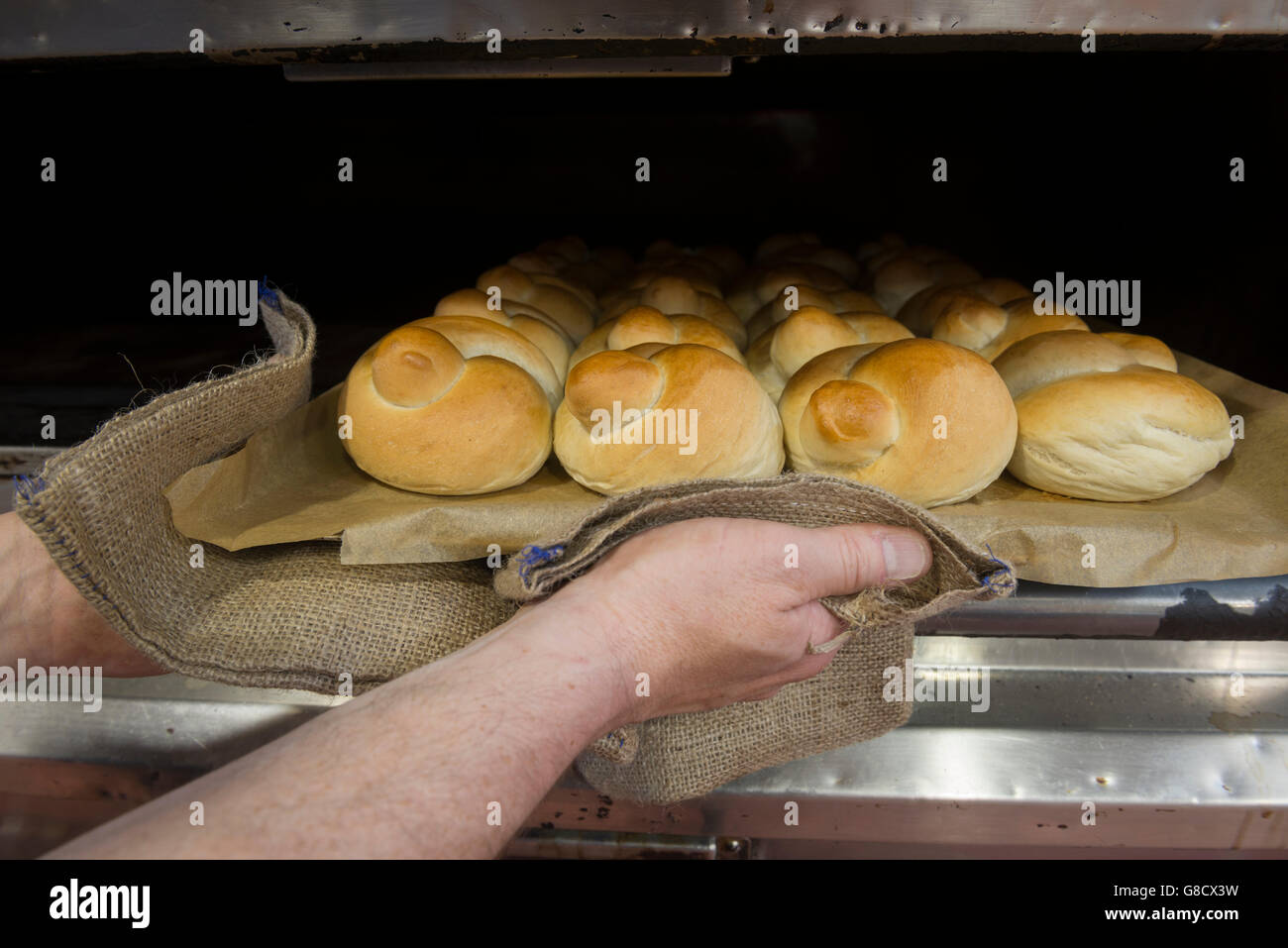 Entfernen von frisch gebackenem Brot Bäcker Brötchen aus dem Ofen. England Stockfoto