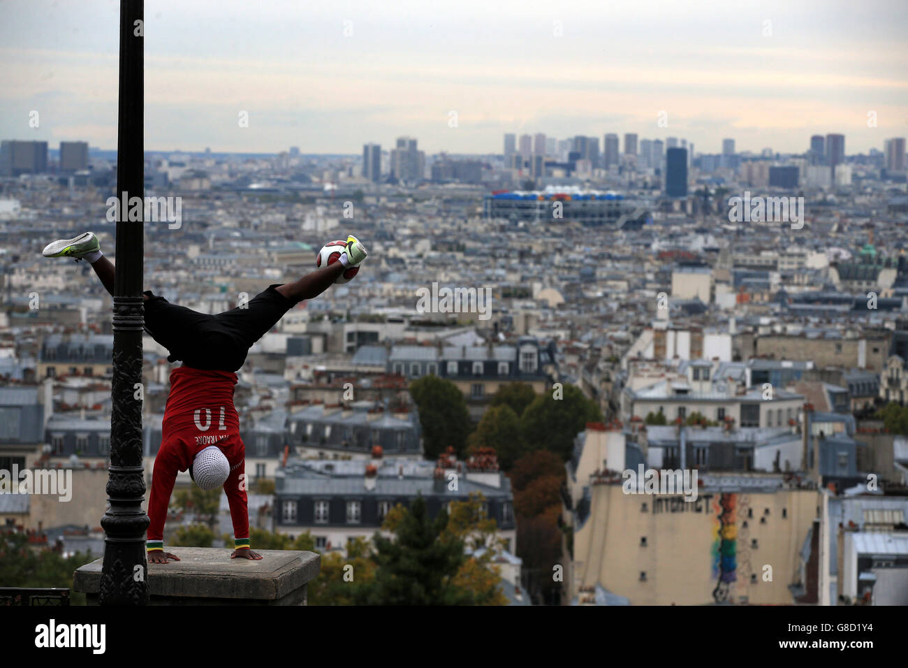 Fußball - UEFA Champions League - Gruppe A - Paris Saint-Germain gegen Real Madrid - Parc des Princes. Ein Jongleur führt bei einem Fußball in Sacre Coeur mit Blick auf die Stadt Paris Tricks durch Stockfoto