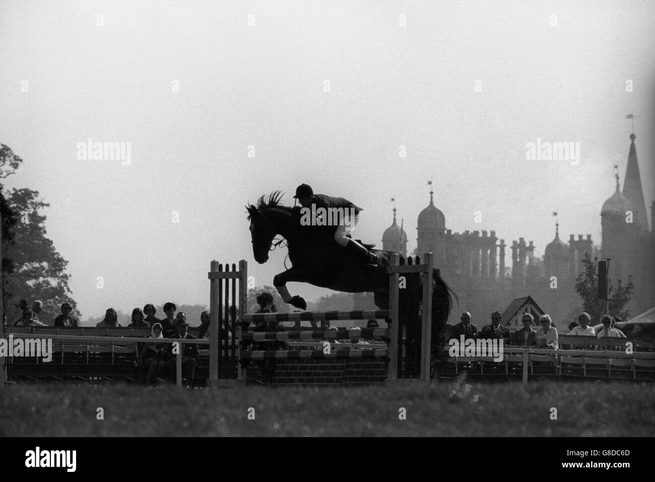 Die Türme des Burghley House, Herrensitz der Marquess of Exeter in Stamford, Lincolnshire, bilden den Hintergrund für Tomby und seine Reiterin, Miss R. Woodward, als sie einen Zaun in den Tally-Ho Stakes räumen, ein "Vorhang-Raiser" für die heutigen Ereignisse in den World Championship Horse Trials. Stockfoto