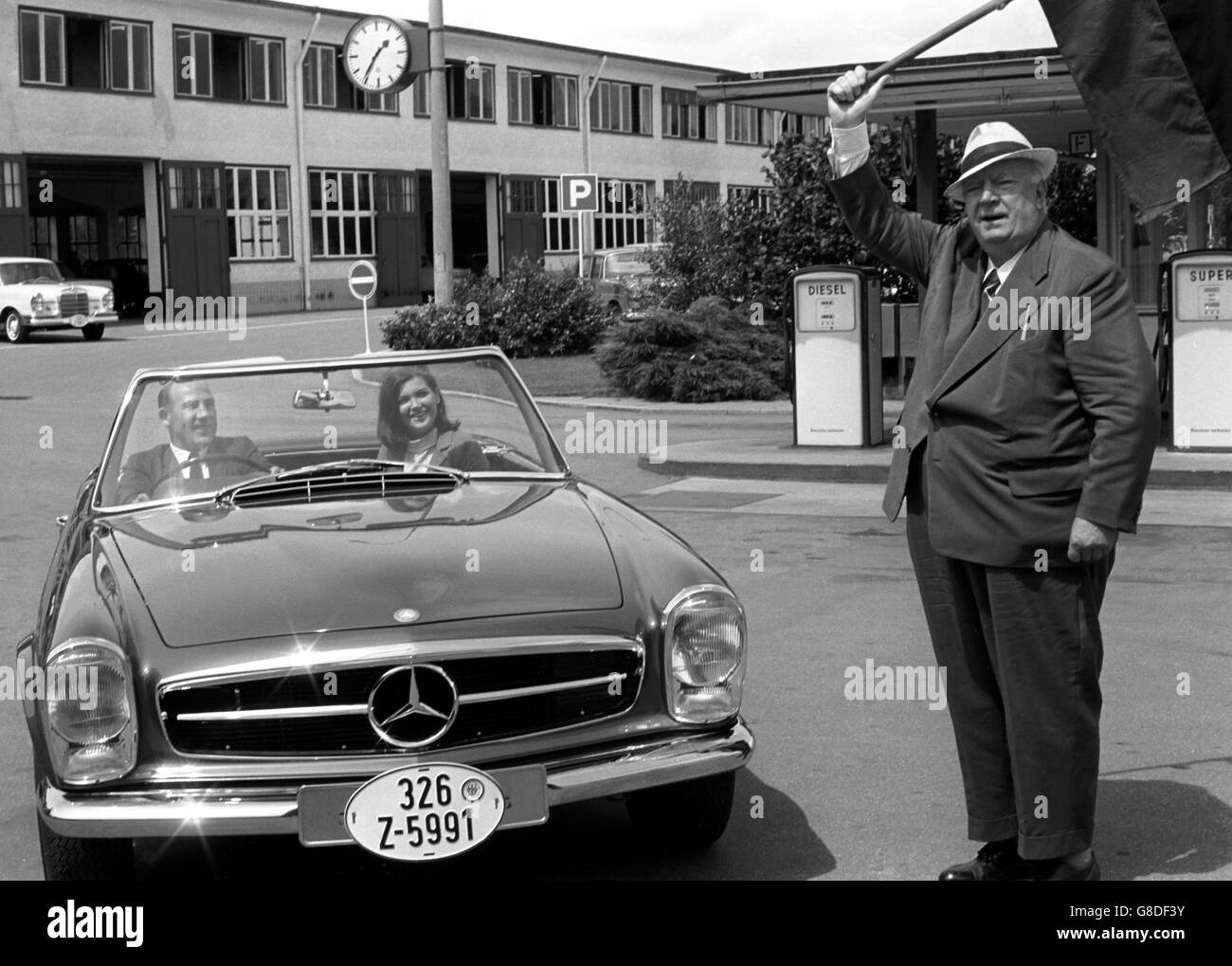 Der ehemalige Rennfahrer Stirling Moss, 36, wurde von seinem alten Chef, Alfred Neubauer, 75, bei seinem Besuch in Stuttgart, Deutschland, zur Abholung seines neuen Mercedes-Benz 230 SL-Sportwagens "weggeschleckt". Auf dem Beifahrersitz sitzt Stirling Moss' Frau Elaine. Stockfoto