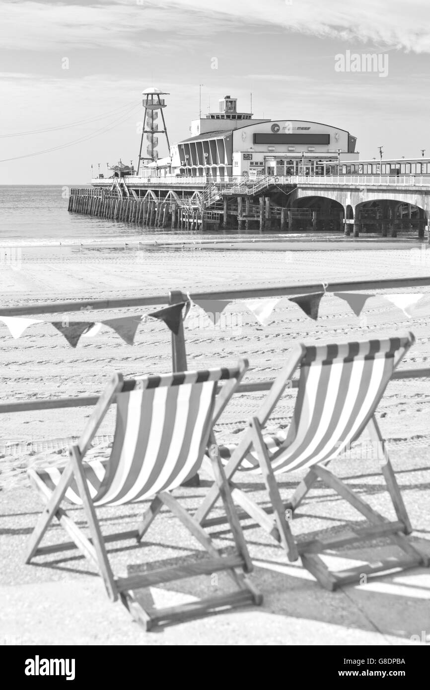 Liegestühle und gestrickte Bunting am Meer mit Bournemouth Strand und Pier im Juni in Monochrom Stockfoto