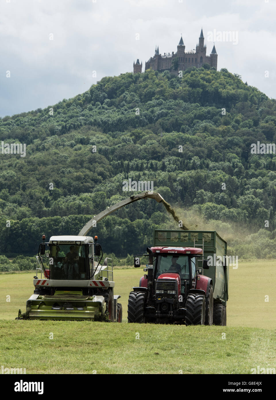 Bisingen, Deutschland. 28. Juni 2016. Eine so genannte Rasen Harvester und ein Traktor Ernte Rasen für das Vieh füttern, mit Burg Hohenzollern im Bild im Hintergrund, in der Nähe von Bisingen, Deutschland, 28. Juni 2016. Foto: PATRICK SEEGER/Dpa/Alamy Live News Stockfoto