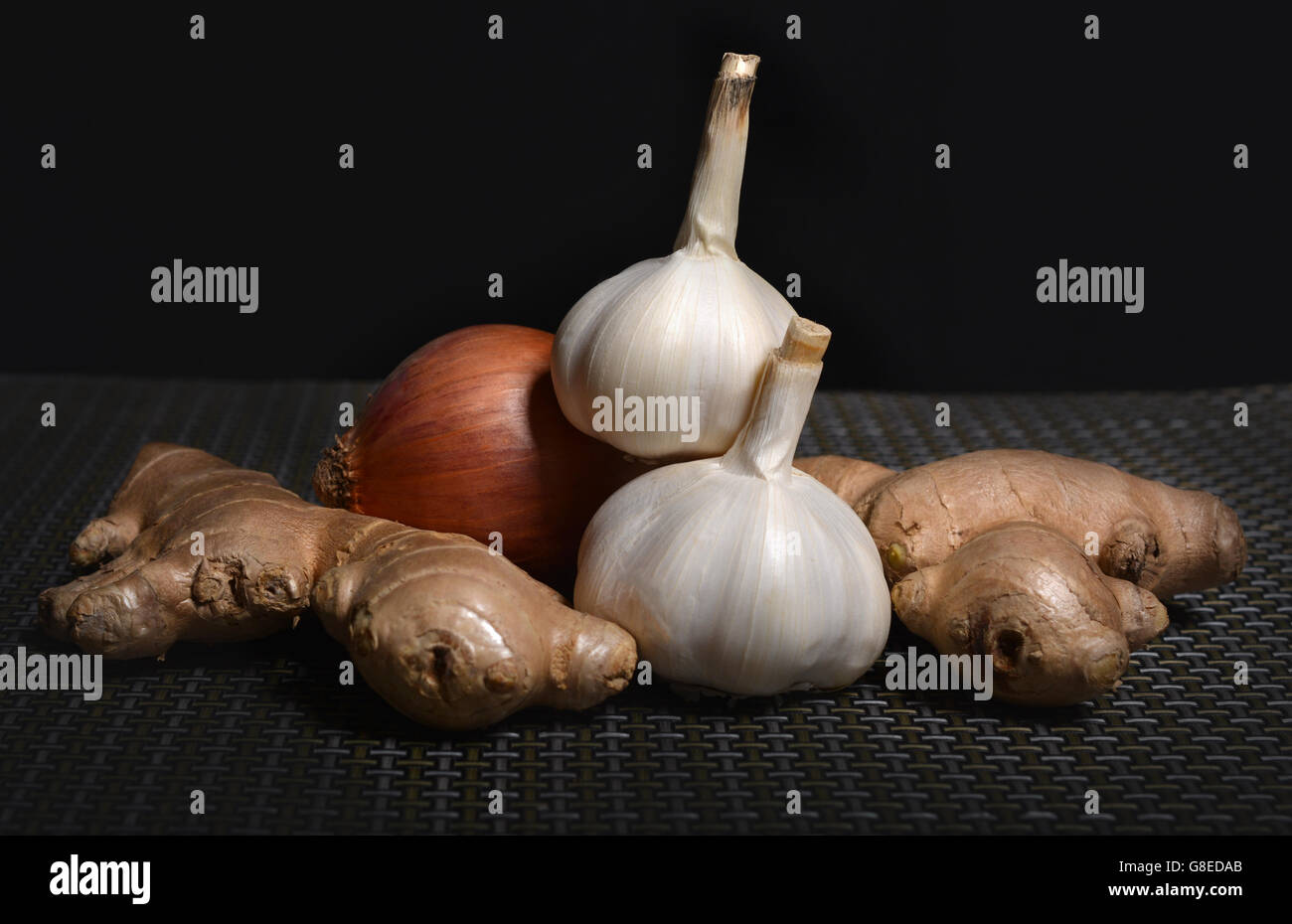 Zwiebel, Knoblauch und Ingwer auf dunklem Hintergrund Licht. Stockfoto