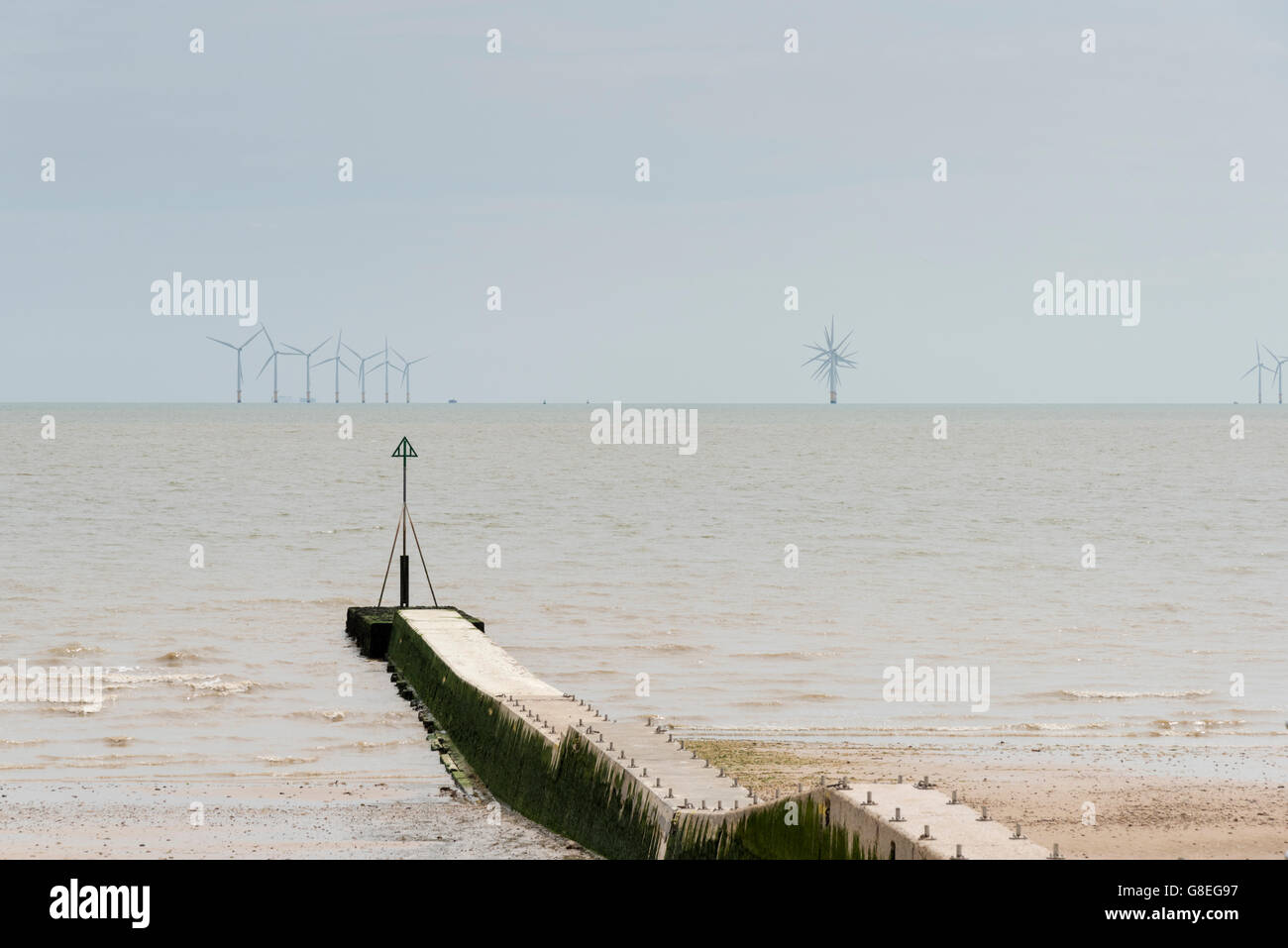 Die Nordsee bei Clacton UK mit Blick über eine Buhne und zu einem Windpark am Horizont. Stockfoto
